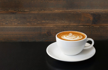 Hot coffee cappuccino latte art on table over wooden background