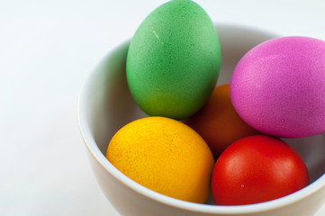 A ceramic bowl full of Easter eggs. The Easter bunny hid the eggs, the children looked for and found the eggs in the morning. There will be Easter breakfast soon.