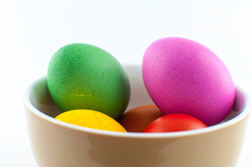 A ceramic bowl full of Easter eggs. The Easter bunny hid the eggs, the children looked for and found the eggs in the morning. There will be Easter breakfast soon.