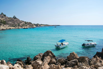 Fototapeta na wymiar Boat on the blue sea on a sunny day at the rocky shore