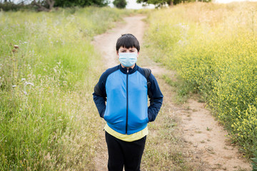 Naklejka premium Boy with backpack and blue jacket prepared to go to school with the mask on his face.