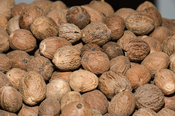 Heap of dry full nutmegs on open market. Fresh mace and nutmeg with selective focus
