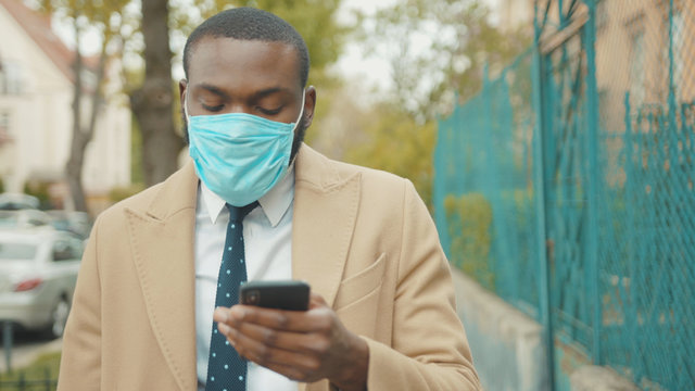 Young African American man wearing face mask look around use phone on street coronavirus safety protection pandemic outbreak medical mask slow motion