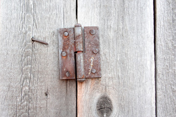  Element of an old gate with rusty metal door hinges.Gray, old boards.