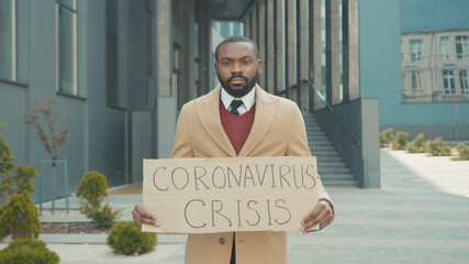 Portrait young african american man wear masks holding poster cardboard with Crisis 2020 jobless...