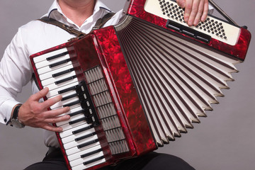 Closeup detail of hands playing a red accordion instrument - obrazy, fototapety, plakaty