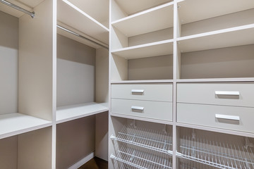 Minimalist white wood walk in closet with wardrobe in neutral beige colors