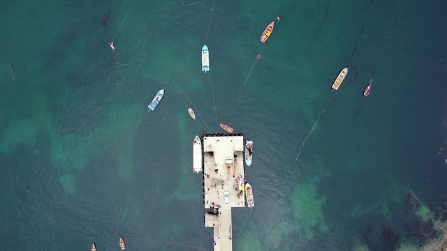 Aerial drone footage of fishermen pier and moored fishing boats. Directly above drone view of small fishing village. Los Lagos, Bahia, Mansa, Pacific coast, Chile.