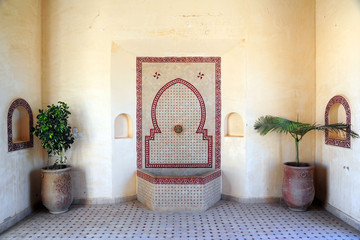 Arabic oriental style fountain with mosaic inside a traditional Moroccan house with plant
