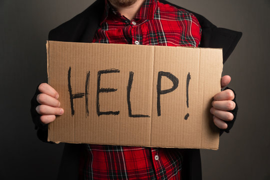 Closeup Of How Men's Hands Hold A Cardboard With The Inscription Asks For Help. Concept Of Helping Everyone