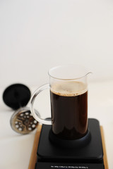 Brewing coffee in french press. On black electronic timer scales.