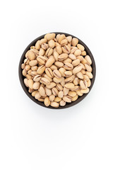 Roasted salty Pistachios  in round bowl on white background, top view