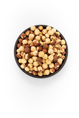 Roasted cleaned hazelnuts in round bowl on white background, top view