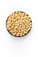 Roasted cleaned hazelnuts in round bowl on white background, top view