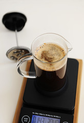 Brewing coffee in french press. On black electronic timer scales.