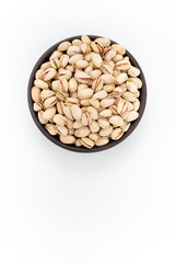 Roasted salty Pistachios  in round bowl on white background, top view