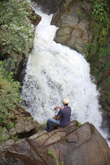 Obraz premium Man enjoying the view of the waterfall in Khlong Wang Chao Kamphaeng Phet National Park, Thailand
