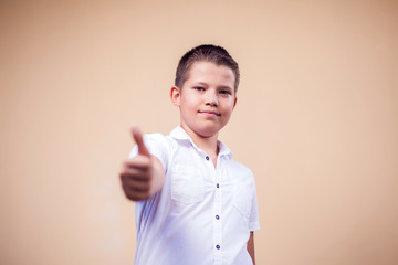 A portrait of kid boy showing thumb up gesture. Childhood and emotions concept