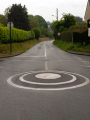 A small intersection roundabout point and an empty road running down and curving.