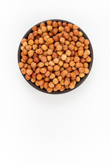 Raw cleaned hazelnuts in round bowl on white background, top view