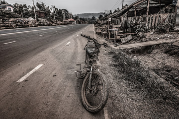Old motorbike standing on the road with old wooden building on background in retro style