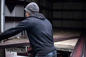 Loaders are loading metal into a lorry. Transportation of heavy industrial products. Men do their job. Small business transporting products. Black work for guys.