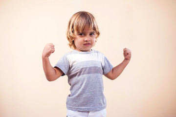 A portrait of kid boy showing strong hands. Childhood and  health concept