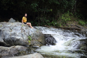 Fototapeta na wymiar Woman sitting at Khlong Nam Lai waterfall in Klong Lan national park, Kamphaeng Phet, Thailand