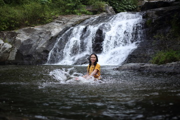 Women enjoying playing in the water at Khlong Nam Lai waterfall in Klong Lan national park, Kamphaeng Phet, Thailand