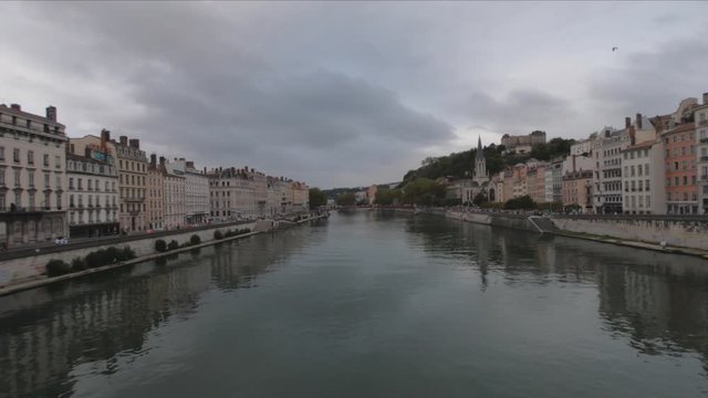 PAN SLOW MO Heading into Vieux Lyon over the Pont Bonaparte. Quai Tilsitt and Quai Fulchiron on the banks of the Saone river, Passerelle, Saint Georges church and Saint-Just College on Fourviere hill.
