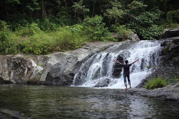Man standing at Khlong Nam Lai waterfall in Klong Lan national park, Kamphaeng Phet, Thailand