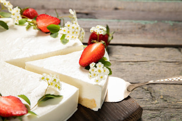Homemade cheesecake decorated with strawberries on a wooden background