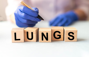 LUNGS word on cube blocks in hands in medical gloves of a female doctor