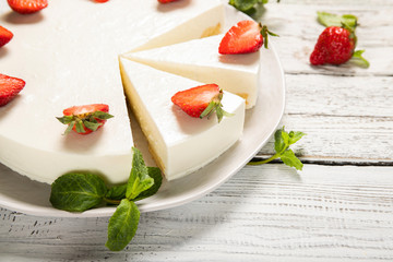 Plate with delicious strawberry cheesecake on a wooden background. Close-up.