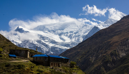 Small town of Ledar with its colorful buildings and the north face of the huge snow-capped Annapurna in the background. Annapurna round trek, circuit