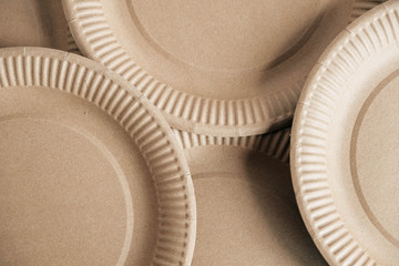 Disposable kraft paper plates as background image. Eco friendly disposable tableware. Top view. Copy, empty space for text