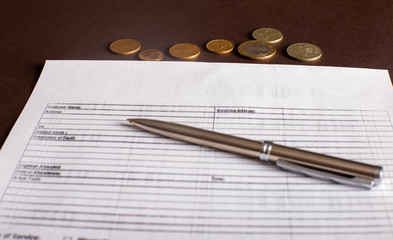 A contract with a pen on it and coins on a dark background