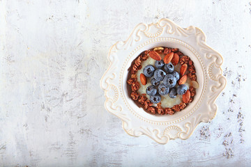 Rice porridge with blueberries or blueberries and almonds in a white plate. Photo of the dish on a white textured background. Copy of the space.
