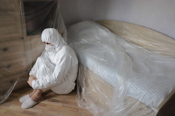 a man in a protective suit in room with Packed furniture during an epidemic, virus and terrible diseases, protection