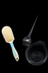 Hair tools hair coloring, cup, brush, hair brush with a white handle isolated on black background. Close-up,  top view