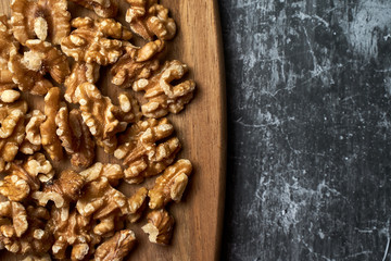 Top view of peeled nuts on a wooden board on a dark background.