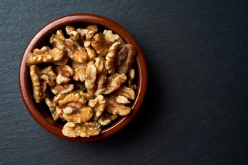 Obraz na płótnie Canvas Ceramic bowl with peeled nuts on a dark background.