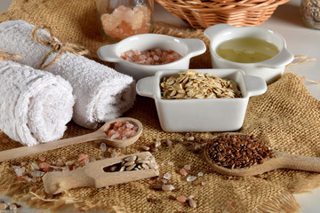linseed, sunflower seeds and pink Himalayan salt on wooden spoons next to various ingredients for the production of homemade face and body cosmetics