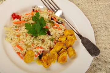 pieces of fried chicken in curry with rice and vegetables on a white plate