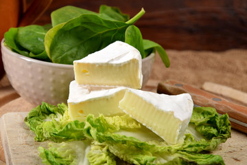 Blue cheese and spinach leaves in a bowl on a wooden kitchen board