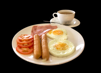 American breakfast with sausage, tomato, ham, fried eggs, bacon, and coffee, black background
