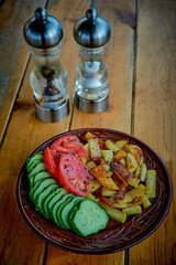 Potatoes, cucumbers and tomatoes on a wooden table.