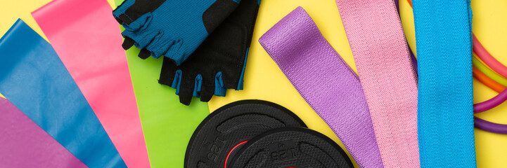 Expanders and elastic bands for fitness with different degrees of load on a yellow background. Elastic bands for fitness. Sports equipment for sports. Banner