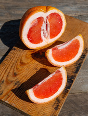 Sliced ​​grapefruit and knife lie on a wooden  background. a bright sunny day