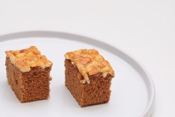 Close up a pair of toffee cake pieces on a plate with white background 